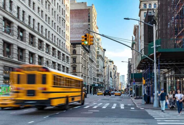 City street with yellow school bus passing under traffic light