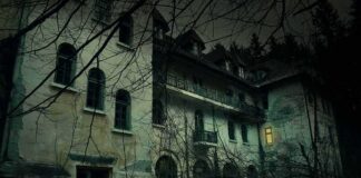 Abandoned mansion at night with one lit window