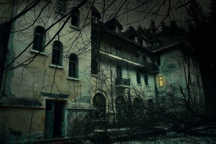 Abandoned mansion at night with one lit window