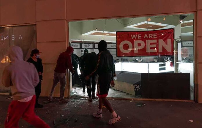 shutterstock_1747500206 People outside a storefront with broken glass at night