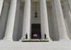 Flag-draped casket on courthouse steps between towering columns