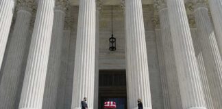 Flag-draped casket on courthouse steps between towering columns