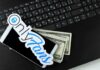 Smartphone with OnlyFans sticker and cash on a laptop keyboard