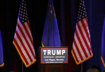Vance Drops In – Michigan Erupts Podium with campaign sign between American flags